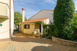 a small white house with a tree next to it at Apartment Red Romantic 2-1 in Bale