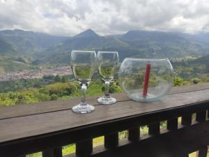 deux verres à vin assis sur un rail en bois avec vue dans l'établissement Cabaña Bambú Noche De Luna, à Jardín