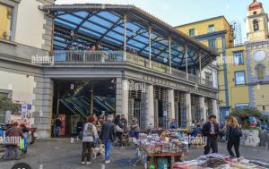 a group of people walking around a market in front of a building at B&B La Cumana in Naples