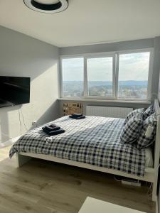 a bedroom with a bed with a checkered blanket and windows at panoramic view and free parking in Vilnius