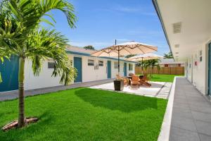 un patio con 2 mesas y una sombrilla en LoKal Rental Tropical Florida destination en Fort Lauderdale
