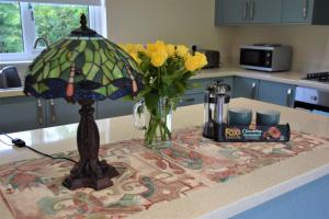 a table with a lamp and a vase of yellow flowers at Ridge View Lodge in Dumfries