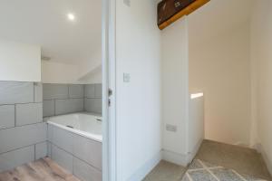 a white bathroom with a tub and a bath tub at 1 Long Barn in Sotherton +30 photos