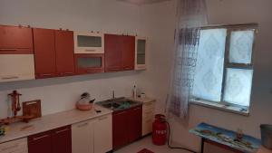 a kitchen with red cabinets and a sink and a window at Дом в селе Сайын Шапагатов in Segendy