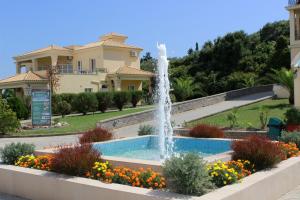 a fountain in a garden in front of a house at Ionian Sea View Hotel - Corfu in Kavos