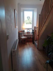 einen Flur mit einer Treppe mit einem Fenster und einem Stuhl in der Unterkunft Village life- Private suite - Living Room, Bedroom and Bathroom in Newtown Saint Boswells