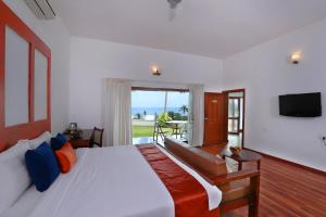 um quarto com uma cama, uma televisão e uma varanda em Getaway Beach Resort Kovalam em Kovalam
