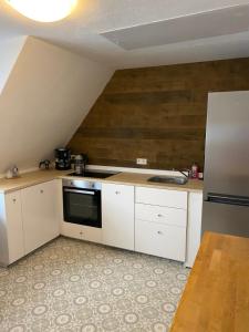 uma cozinha com armários brancos e um forno com placa de fogão em Ferienhaus Angela em Dankern