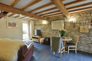 sala de estar con mesa y pared de piedra en Critchlow Cottage en Buxton