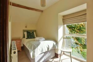 1 dormitorio con cama, ventana y silla en Critchlow Cottage en Buxton