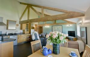 a kitchen and living room with a table with flowers on it at Sheldon Cottage in Buxton