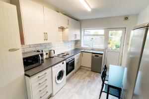 uma cozinha com armários brancos e uma máquina de lavar e secar roupa em Spacious 6 Bedroom House Close to Beaches and Town em Bournemouth