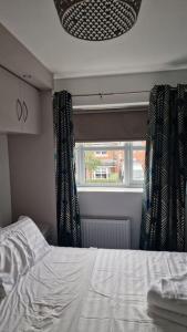 博爾頓的住宿－Well Furnished 3 Bedroom House in a cosy estate in Bolton，一间卧室配有床和带窗帘的窗户