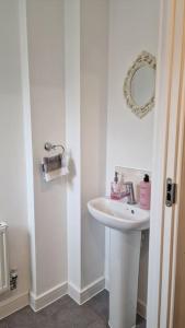 La salle de bains blanche est pourvue d'un lavabo et d'un miroir. dans l'établissement Well Furnished 3 Bedroom House in a cosy estate in Bolton, à Bolton