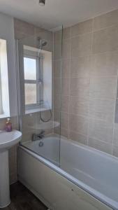 La salle de bains est pourvue d'une douche, d'une baignoire et d'un lavabo. dans l'établissement Well Furnished 3 Bedroom House in a cosy estate in Bolton, à Bolton