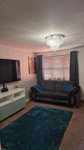 ein Wohnzimmer mit Sofa und Fernseher in der Unterkunft Well Furnished 3 Bedroom House in a cosy estate in Bolton in Bolton