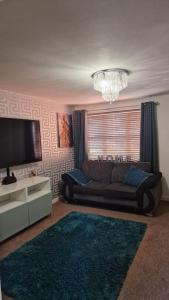a living room with a couch and a television at Well Furnished 3 Bedroom House in a cosy estate in Bolton in Bolton