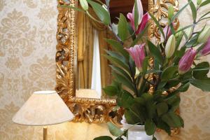 a mirror and a lamp and a vase with flowers at Casa dei Cavalieri in Venice