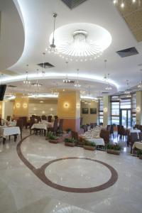 ein Restaurant mit Tischen und Stühlen und einem großen Kronleuchter in der Unterkunft Mari Vila Hotel in Bukarest