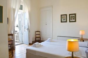 a bedroom with two beds and a table with a lamp at Hotel Omiros in Ermoupoli