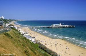 Ein Strand mit einem Pier und einem Haufen Leute in der Unterkunft Spacious 6 Bedroom House Close to Beaches and Town in Bournemouth