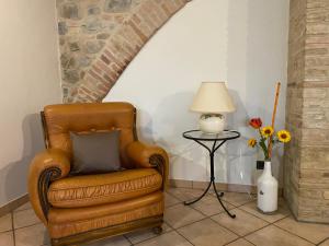 una sedia marrone seduta accanto a una lampada e un vaso di fiori di Agriturismo Il Pozzo a Castiglione dʼOrcia