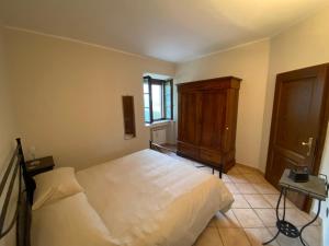 una camera con letto bianco e armadio in legno di Agriturismo Il Pozzo a Castiglione dʼOrcia