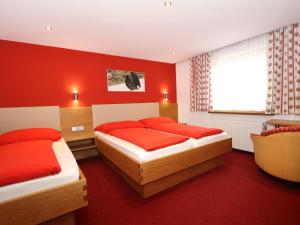 a bedroom with two beds and a red wall at Rudigier in Kappl