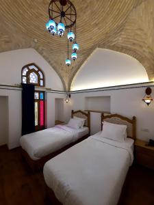 a bedroom with two beds and a chandelier at Marhaba boutique Madrasah 15th-16th century in Bukhara