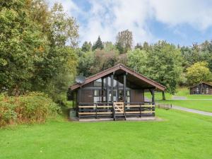 a small cabin in a grassy field with trees at Firbush Lodge in Killin