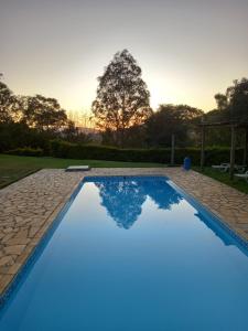 a blue swimming pool in a yard with a sunset at Pousada Ecológica Rio do Peixe in Socorro