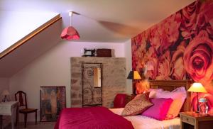 1 dormitorio con 1 cama y una pared con flores en Les jardins de Nanine, en Lapleau