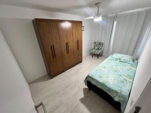 Un dormitorio con una cama y un armario de madera. en Residence club Praia dos Anjos, en Arraial do Cabo 8 fotos más