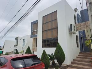 a red car parked in front of a white building at Relax Habitación Privada in Manta