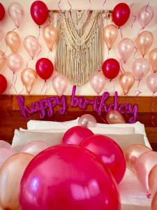 een hoop ballonnen en een happy birthday bord op een bed bij Dreamer Palomino in Palomino