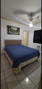 a bedroom with a blue bed and a flat screen tv at Apartamento Guarujá in Guarujá