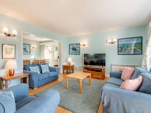 a living room with two blue couches and a television at Advantage Point in West Lulworth