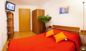 ein Schlafzimmer mit einem roten Bett mit orangefarbenen und gelben Kissen in der Unterkunft Apartments Shock in Cerkno