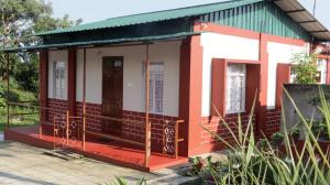 - un petit bâtiment rouge et blanc avec une terrasse couverte dans l'établissement K & K INN, à Cherrapunji