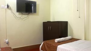 a bedroom with a small cabinet and a tv on the wall at K & K INN in Cherrapunji