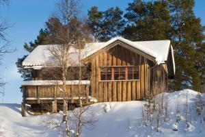 una cabaña de madera en la nieve con nieve en Bruksvallarna Lullens stugby en Bruksvallarna