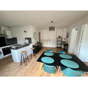 ein Wohnzimmer mit einem Tisch und blauen Stühlen in der Unterkunft T2 rénové avec parking gratuit sur place in Valence