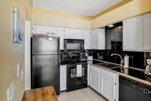 a kitchen with white cabinets and a black refrigerator at Ocean Vue in New Smyrna Beach +14 photos