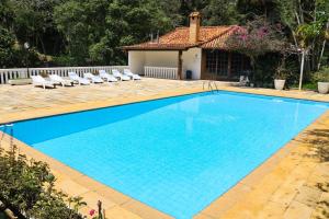 a swimming pool with chairs and a house at Vila da Sol Itaipava casas e estúdios in Itaipava