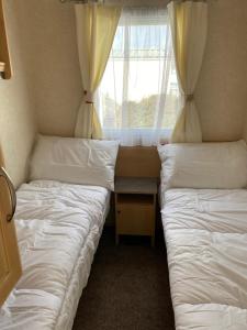 two beds in a small room with a window at Rejuven8 Rentals - Silver Beach - Ingoldmells - Skegness in Ingoldmells