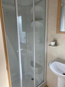 a shower with a glass door next to a sink at Rejuven8 Rentals - Silver Beach - Ingoldmells - Skegness in Ingoldmells