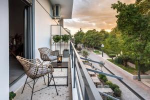 een balkon met stoelen en een tafel en uitzicht op een straat bij Eleusis Suites Β in Elefsina