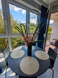 una mesa con dos sillas y un jarrón con flores. en Apartament Blue BB, en Bielsko-Biala