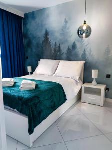 a bedroom with a large bed with a painting on the wall at Apartament Blue BB in Bielsko-Biała