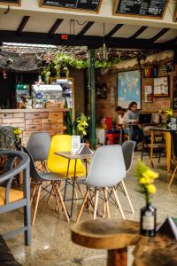 Panela Coffee Hostel في ميديلين: مطعم فيه كراسي وطاولات وناس فالخلفية